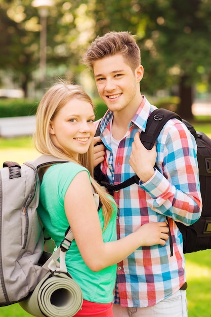 conceito de viagens, férias, turismo e amizade - casal sorridente com mochilas na natureza