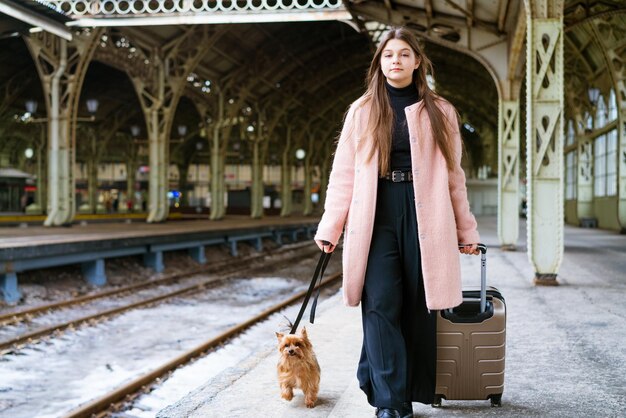 Conceito de viagens na estação jovem turista com cachorro vai e arrasta a mala com e procura o hotel na ...