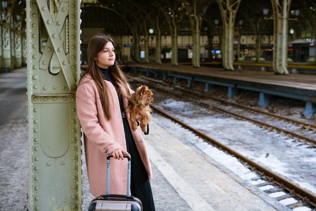 Conceito de viagens na estação jovem turista com cachorro vai e arrasta a mala com e procura o hotel na ...