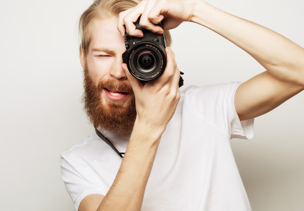 Conceito de viagens, tecnologia e estilo de vida: jovem fotógrafo barbudo tirando fotos com câmera digital.