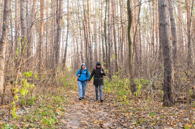 Conceito de viagens, turismo, caminhada e pessoas - casal de turistas na floresta de outono.