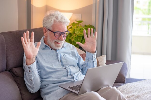 Conceito de videochamada Feliz sênior aposentado acenando com as mãos videochamada por laptop