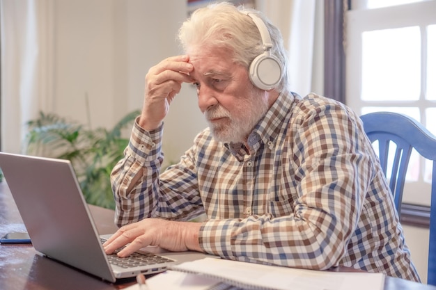 Conceito de videoconferência Homem barbudo concentrado sentado à mesa com laptop e livros trabalhando tecnologia