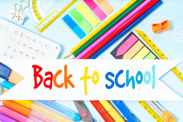 Conceito de volta à escola com suprimentos escolares em fundo azul com saudações de volta ao cu