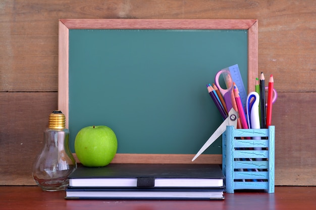 Conceito de volta às aulas com maçã na mesa em frente ao quadro-negro