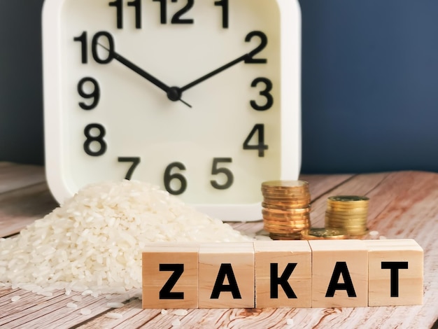 Conceito de zakat. Frase ZAKAT escrita em post-it com arroz no saco, moedas e despertador.