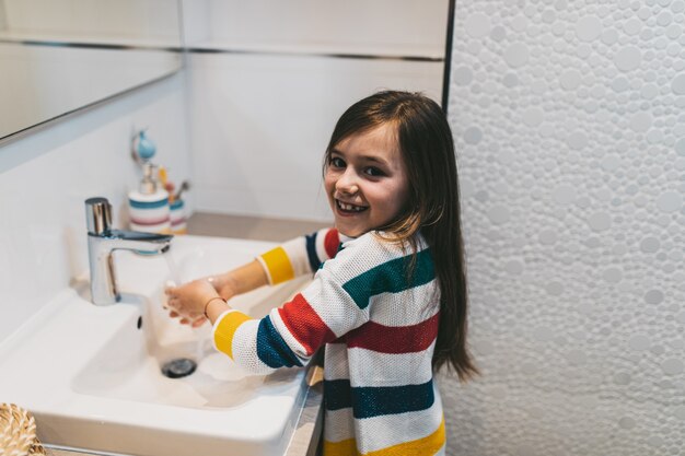 Conceito do coronavirus covid-19. menina lavando as mãos no banheiro com sabonete antibacteriano.