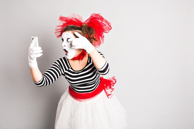 Conceito do dia da mentira. Mime segurando o telefone celular.