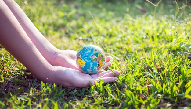 Foto conceito do dia da terra ou do dia mundial do meio ambiente salve nosso planeta e floresta globo na mão na grama verde