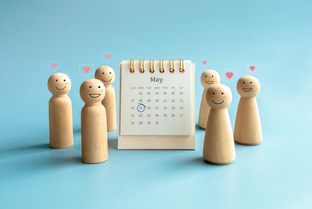Conceito do Dia Internacional da Família Marca do círculo na data de 15 de maio de 2023 no calendário da mesa da página do mês de maio perto de figuras de madeira sorridentes felizes pessoas com ícone de amor em fundo azul claro