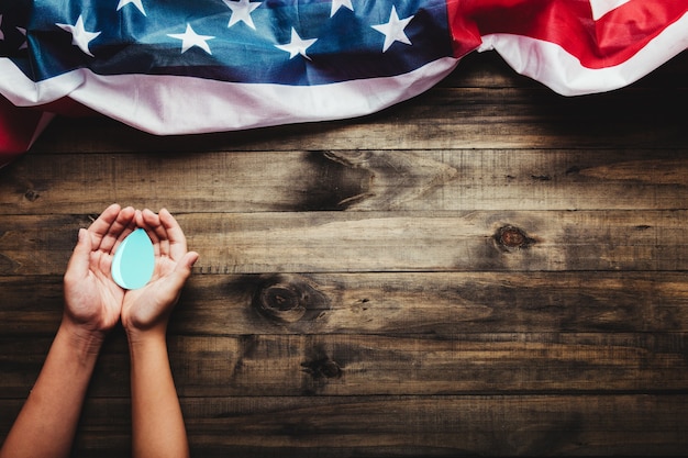 Conceito do Dia Mundial da Água Mãos segurando uma gota d'água em um fundo de madeira e a bandeira dos EUA