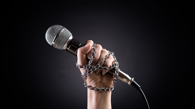 Conceito do Dia Mundial da Liberdade de Imprensa Mão segurando um microfone com corrente