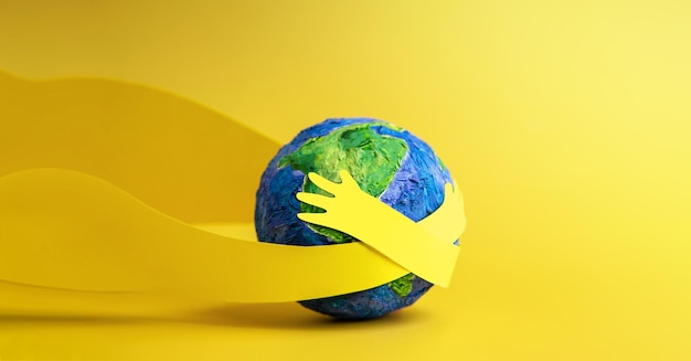 Foto conceito do dia mundial da terra energia verde esg recursos renováveis e sustentáveis cuidados com o meio ambiente papel cortado com as mãos abraçando o globo verde vista de cima