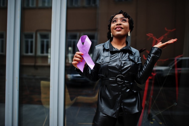 Conceito do Dia Mundial do Câncer, 4 de fevereiro. Mulher afro-americana segura a consciência da fita roxa.