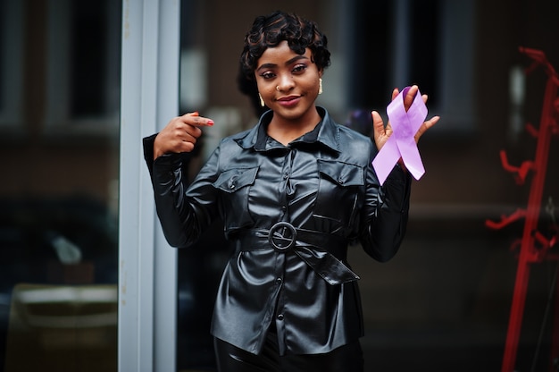 Conceito do Dia Mundial do Câncer, 4 de fevereiro. Mulher afro-americana segura a consciência da fita roxa.