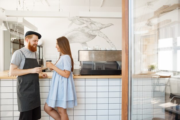 Conceito do negócio do café - o bartender barbeado inteligente novo gosta de falar e de dar uma xícara de café para o cliente bonito.