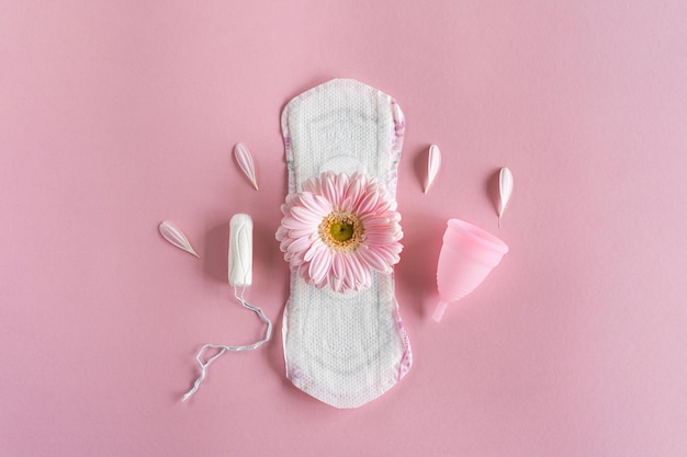 Foto conceito do período menstrual almofada feminina higiênica branca copo menstrual e tampão com flores cor-de-rosa