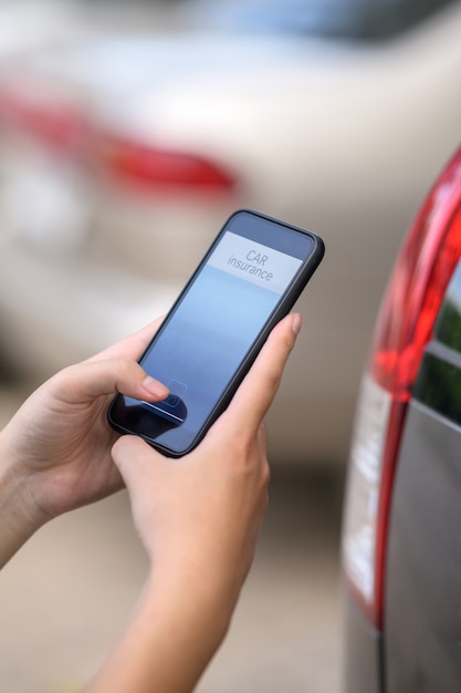 Conceito do seguro de carro, mão do homem que guarda a aplicação do seguro de carro no telefone celular.