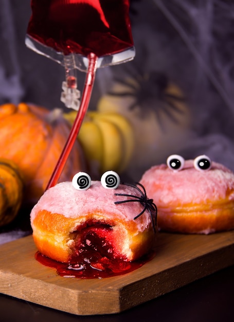 Conceito engraçado do feriado de halloween. donuts com geléia em uma tábua de madeira