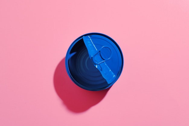 Conceito estético com lata pintada de azul na superfície rosa