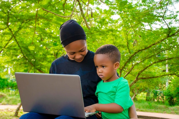 Conceito horizontal de mãe e filho felizes usando o laptop do lado de fora