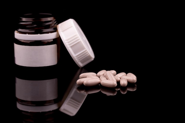 Conceito médico de comprimidos prescritos e garrafa em fundo preto com espaço de cópia de reflexão