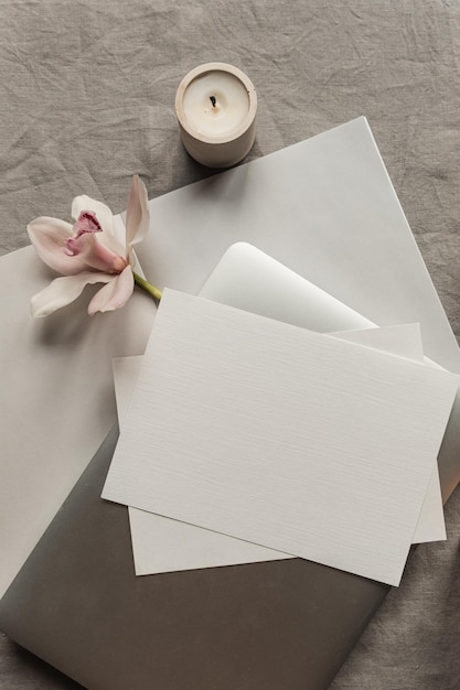 Foto conceito minimalista boêmio de luxo estético traçado de recorte em branco folha de papel cartão de convite computador portátil vela de flor rosa em pano de linho neutro vista superior plana