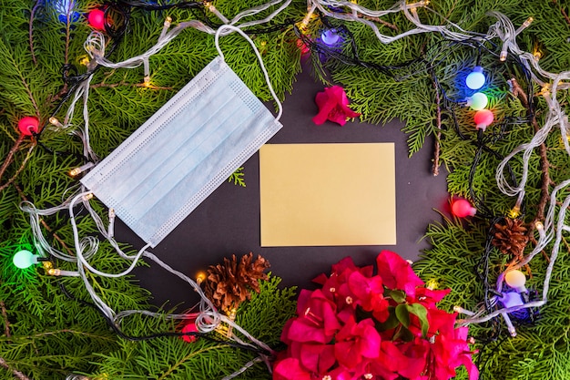 Conceito minimalista do fundo do Natal. Cartões de Natal com decorações de folhas de abeto, luzes, flores de papel (buganvílias) e máscaras. Ideia. Natal, inverno, Flat lay, vista de cima