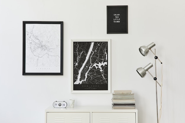 Conceito moderno de mapas de dois pôsteres com cômoda branca, decoração, livro e acessórios pessoais elegantes