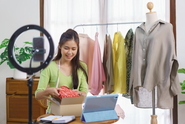 Conceito online de roupas de moda Blogueira feminina embalando vestido novo em caixa para preparar o envio ao cliente