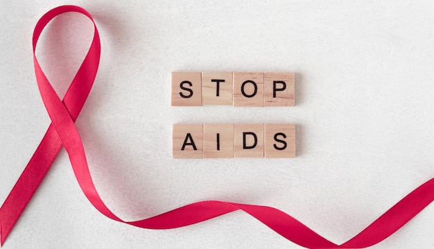 Conceito para o Dia Mundial da AIDS. Fita vermelha perto de letras de madeira. Baner, copie o espaço. pare a AIDS