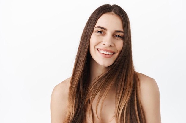 Conceito perfeito de pele e cuidados com os cabelos. Rosto bonito de mulher adulta com maquiagem natural, sem rugas, cosméticos com efeito lifting anti-envelhecimento, dentes brancos sorridentes, cabelo brilhante longo e saudável