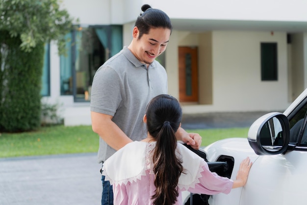 Conceito progressivo de pai e filha com carro EV e estação de carregamento doméstico