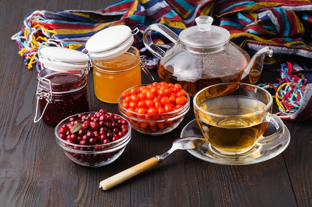 Conceito saudável. Chá de bagas de inverno com cranberries, mel e tomilho em um copo de vidro na mesa de madeira. Alternativa à medicina tradicional
