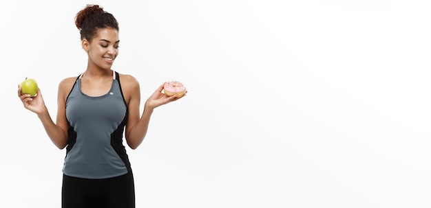 Conceito saudável e de dieta, o belo afro-americano desportivo toma uma decisão entre donut e verde