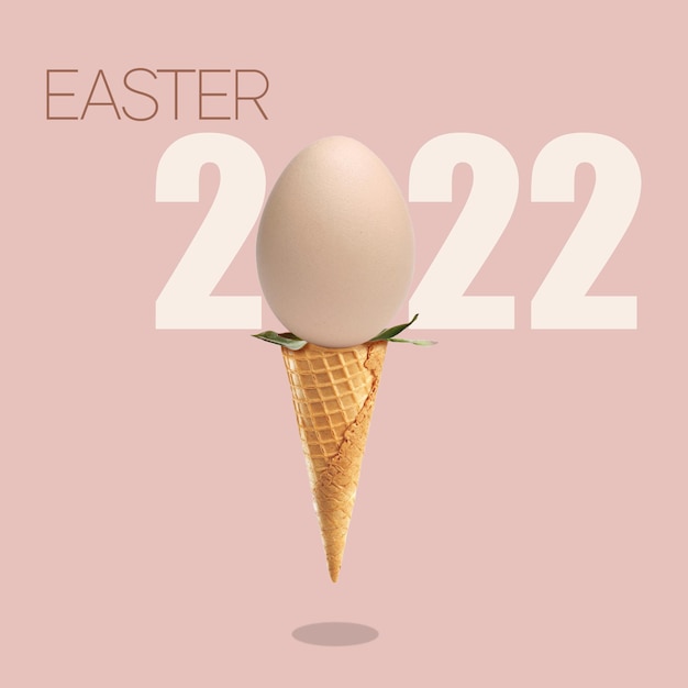 Conceito sobre o tema do ovo de Páscoa 2022 como símbolo do feriado em uma casquinha de sorvete em um fundo rosa com um cartão postal de sombra
