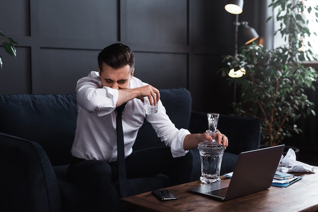 Conceitos de alcoolismo ou problemas de vida. Empresário chateado bebe vodka.