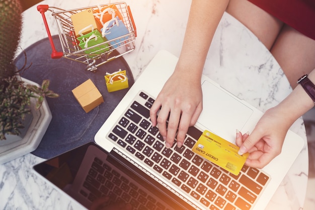 Foto conceitos de compras online, mãos de mulher usando cartão de crédito e computador portátil