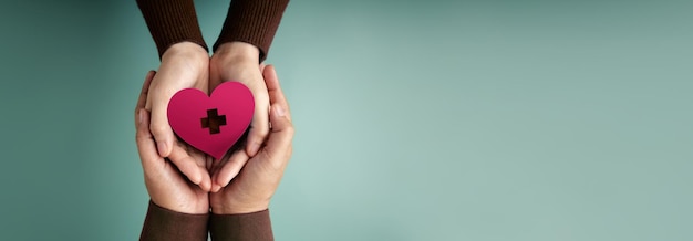 Foto conceitos de doação mãos de pessoas voluntárias abraçando um símbolo de coração com um sinal da cruz vermelha juntos amor cuidados de saúde doação e caridade vista superior