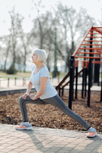 Concentración. Mujer de edad concentrada vistiendo ropa deportiva y haciendo ejercicio al aire libre