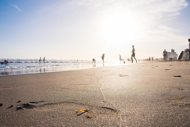 Concentración selectiva en el reflejo del sol en la arena de la playa llena de turistas