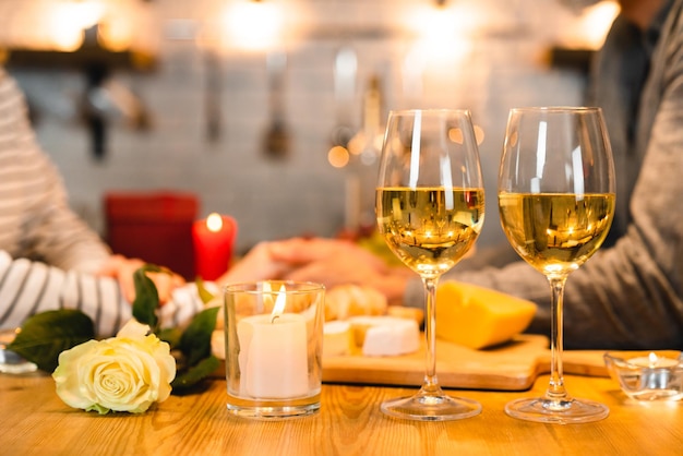 Concentrado no jantar romântico com vinho e rosas e amantes de mãos dadas no fundo