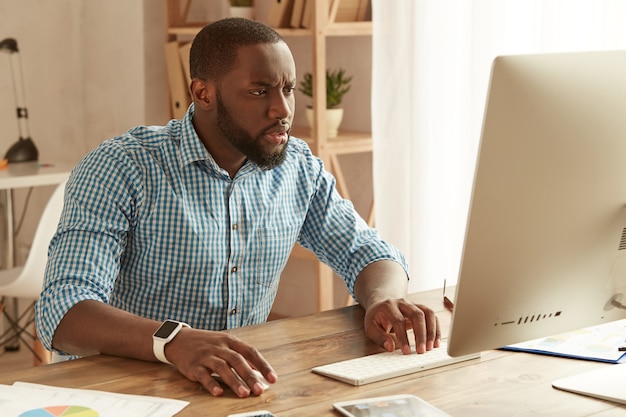 Concentrado no trabalho empresário afro-americano trabalhando remotamente com foco jovem afro-americano em