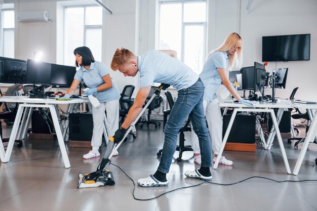 Concentrado en el trabajo Grupo de trabajadores limpian la oficina moderna juntos durante el día