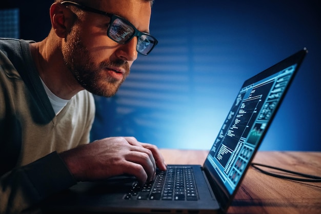 Concentrado en el trabajo El programador masculino está trabajando en el interior con una computadora portátil