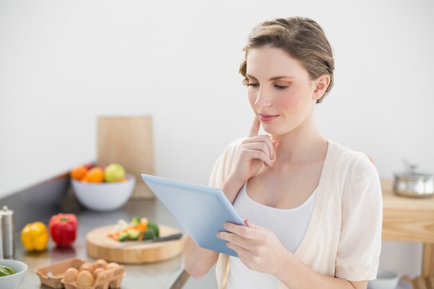 Concentrando a jovem usando seu comprimido em sua cozinha