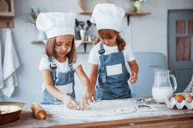 Concentrarse en cocinar. Niños de la familia en uniforme de chef blanco preparando la comida en la cocina.