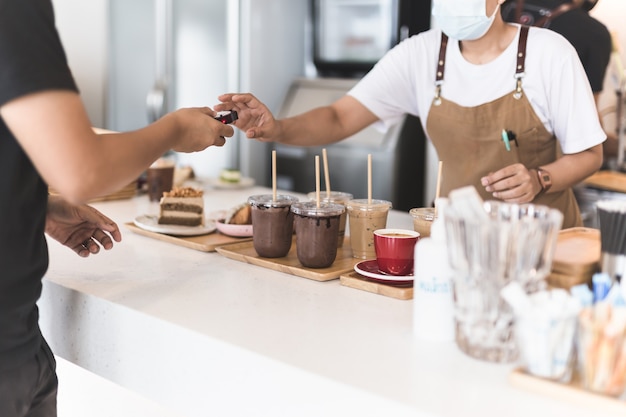 Concentre-se na bebida de chocolate gelado com a garçonete pegando pagers digitais do cliente