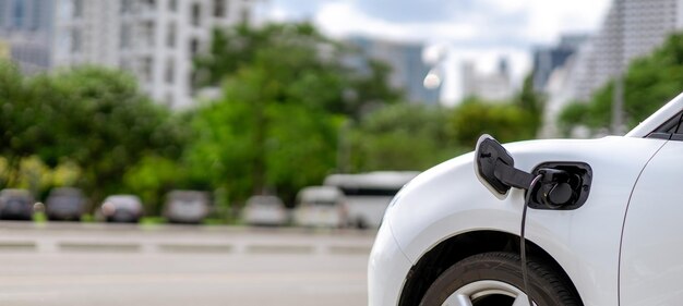 Concentre-se no carro EV e carregador com desfoque de fundo para o conceito progressivo