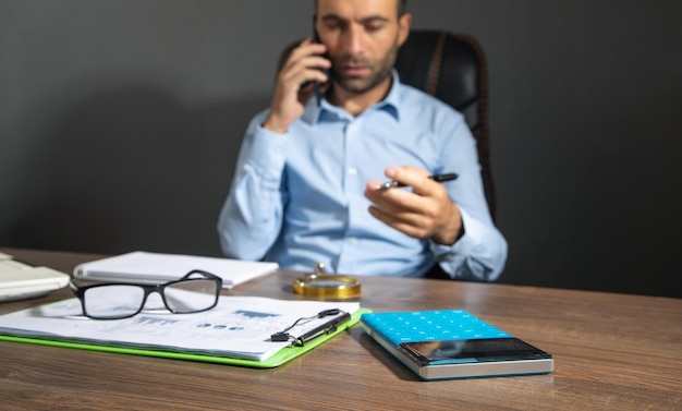 Concéntrese en la calculadora con un hombre que usa un teléfono inteligente